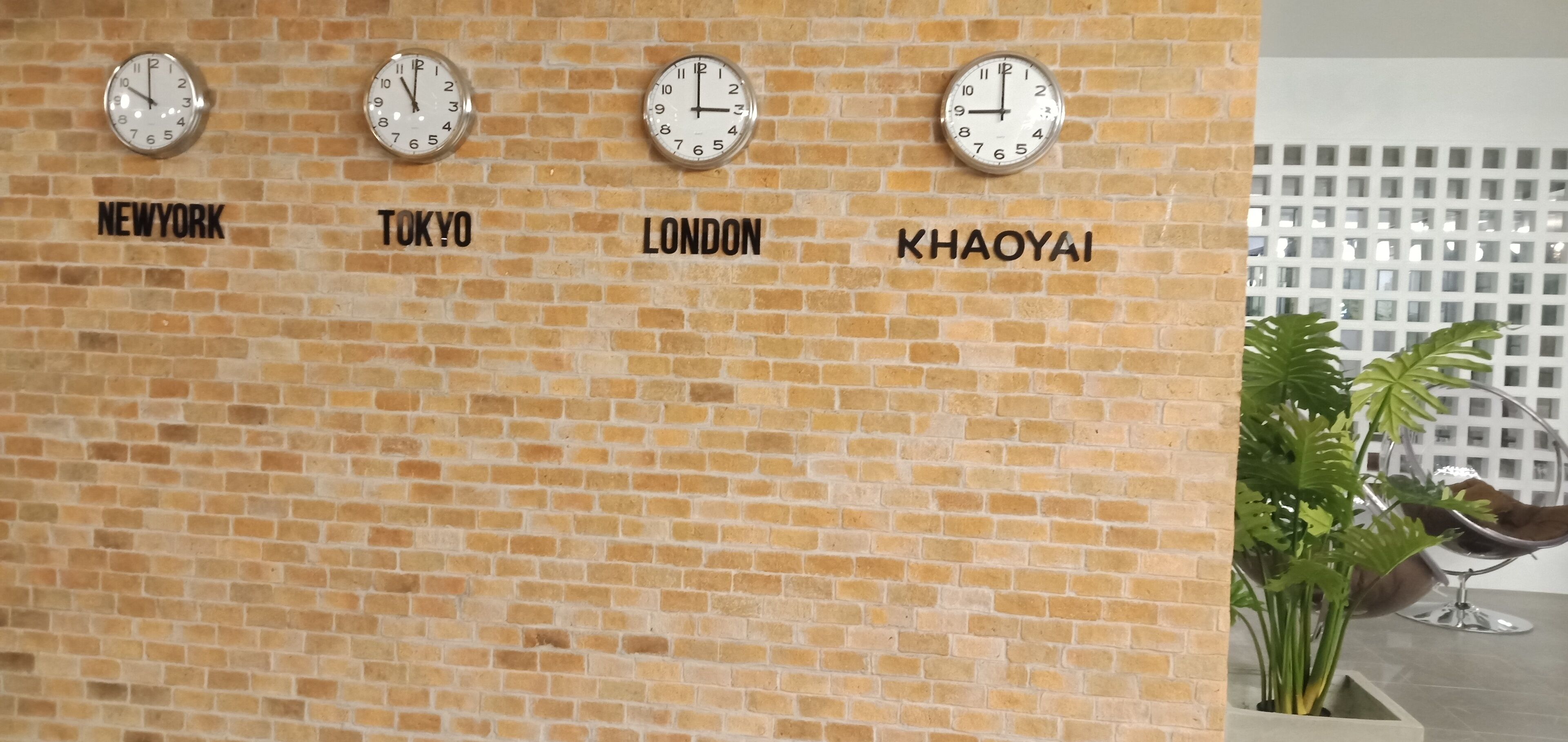 A wall with clocks labeled with city names: New York, Tokyo, London, and Khaoyai.