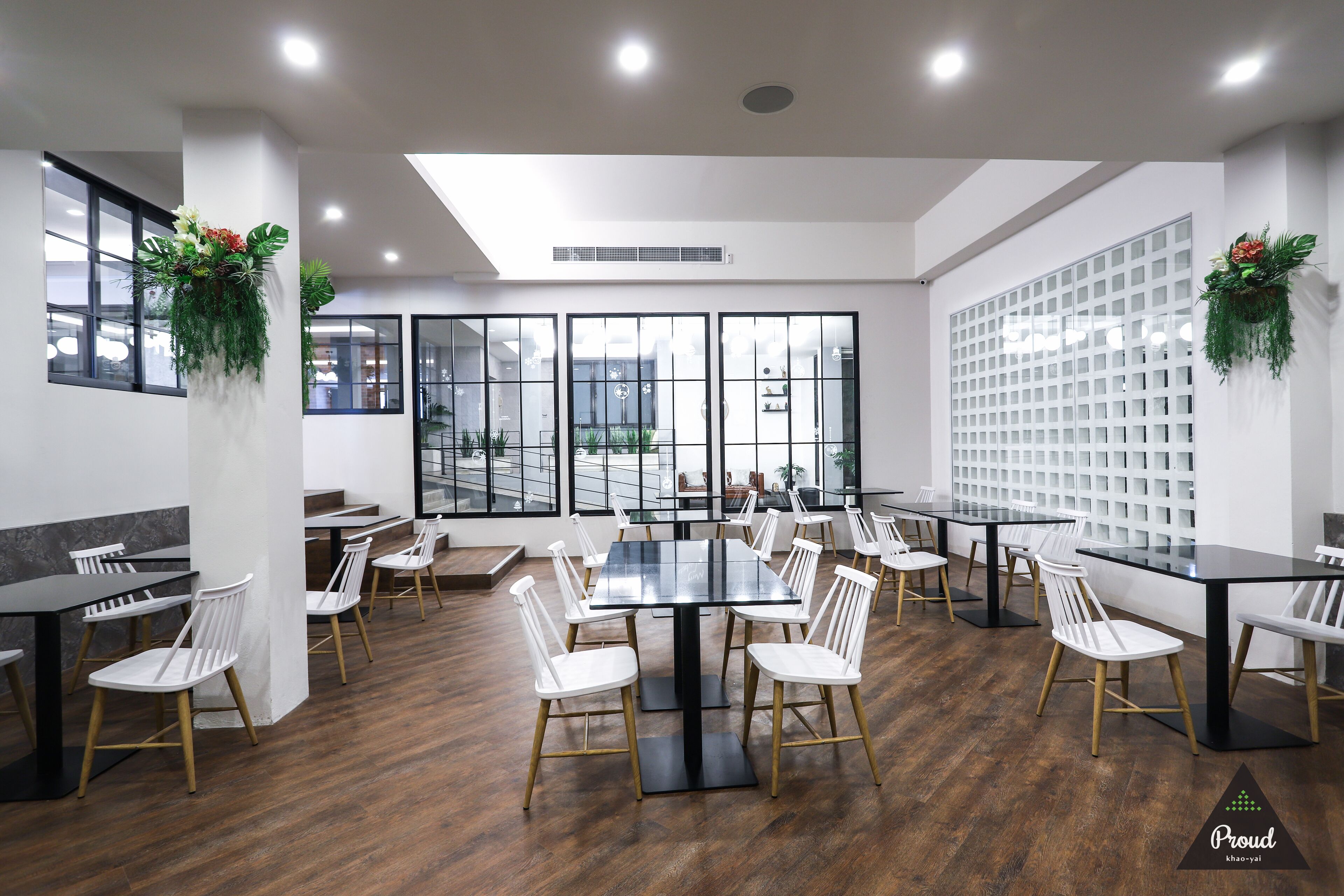 Une salle de conférence moderne avec des cloisons en verre, des chaises blanches et des tables noires.