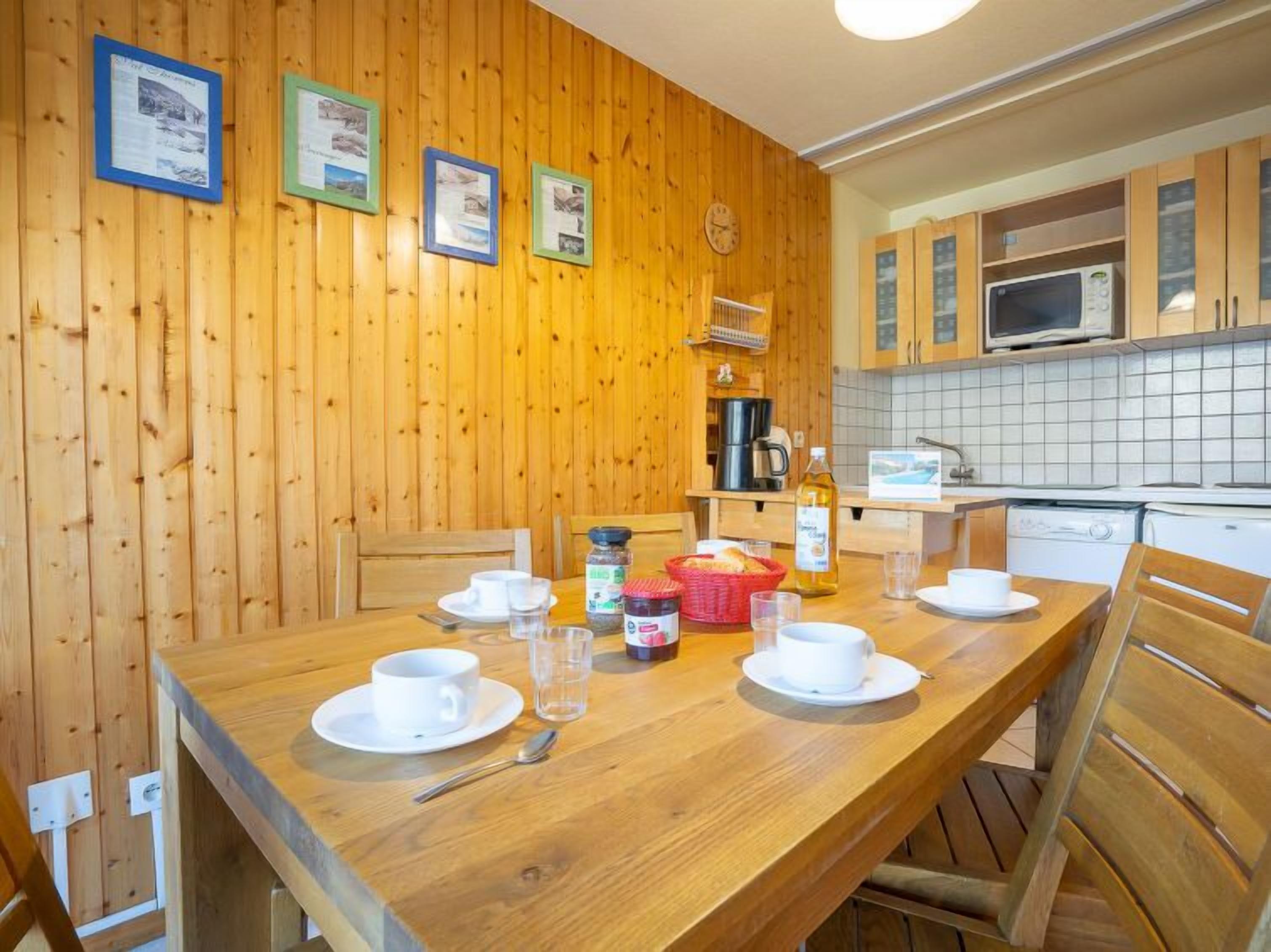 Una habitación con paneles de madera, una mesa de comedor para dos personas, un microondas y una cafetera.