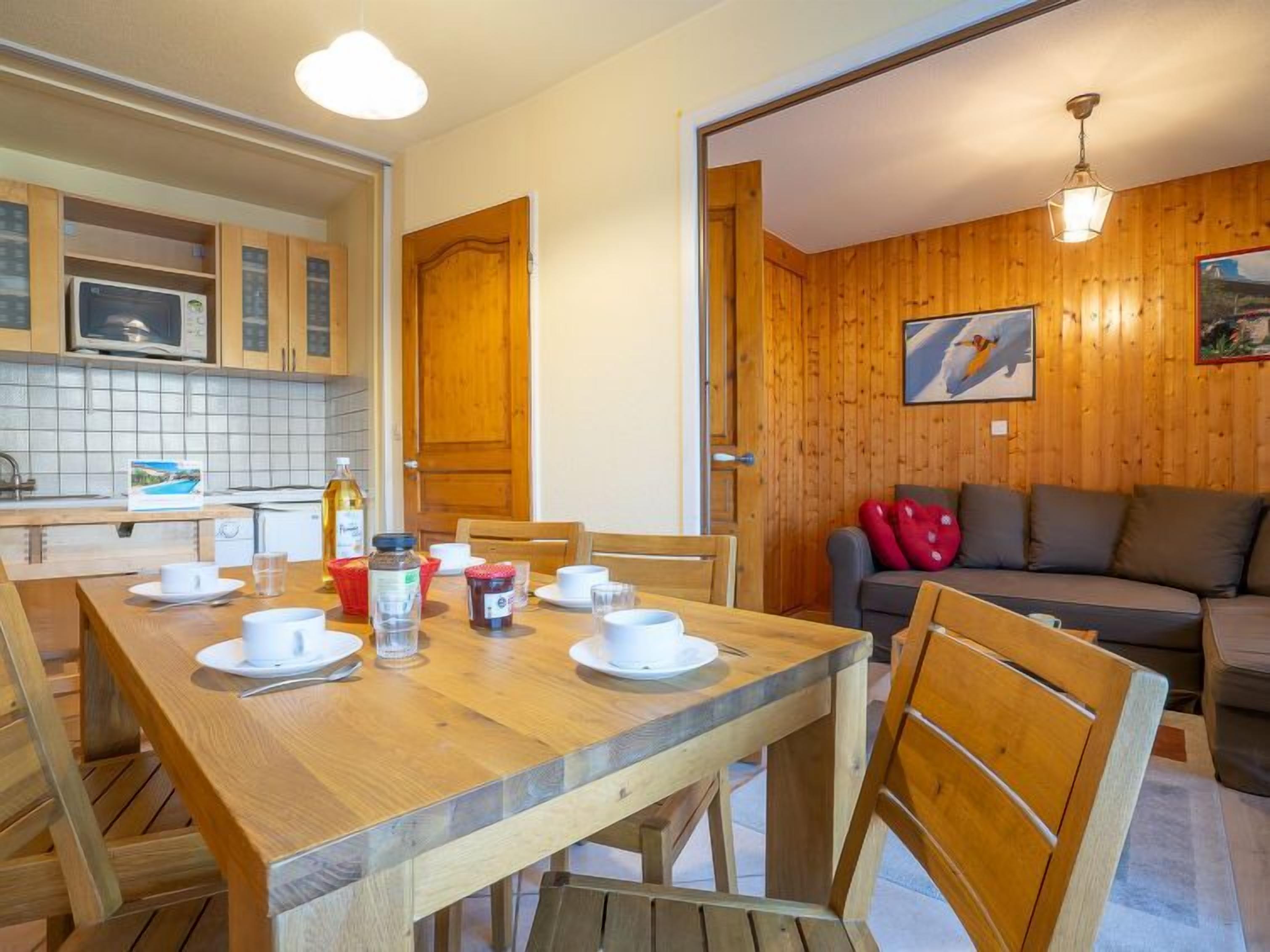 A wooden-paneled room with a dining table set for four, a sofa, and a painting on the wall.