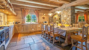 Una cucina rustica con mobili in legno, un piano di lavoro in pietra e un'area pranzo con tavolo apparecchiato per quattro.