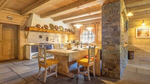 Una cucina rustica con travi in legno, una colonna in pietra e un'area pranzo con sedie di legno.
