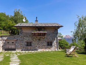Una casa de piedra con balcón, terraza de madera y vistas a la montaña.