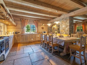 Una cocina rústica con suelo de piedra, armarios de madera y un comedor con mesa dispuesta para cuatro.