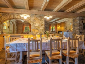 Un comedor rústico con paredes de piedra, vigas de madera y un arco de piedra.