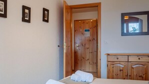 A hotel room with a bed, a wooden wardrobe, and a door leading to another room. - Victoria 1 C1 by Interhome (Nendaz)