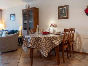 Un coin repas avec une table dressée pour quatre personnes, un meuble avec des portes en verre, un canapé et un tableau encadré au mur.