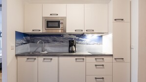 Eine moderne Küche mit weißen Schränken, einer Edelstahl-Mikrowelle, einer Kaffeemaschine und einem Spülbecken.