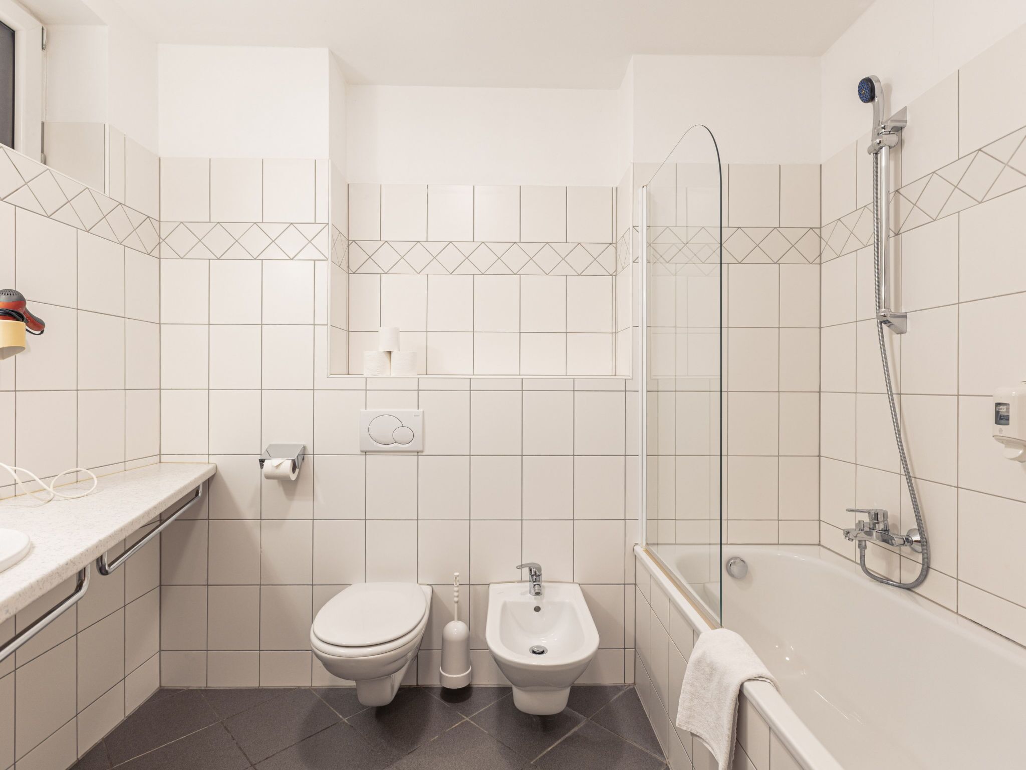 Ein modernes Badezimmer mit Toilette, Bidet, Waschbecken und Badewanne.