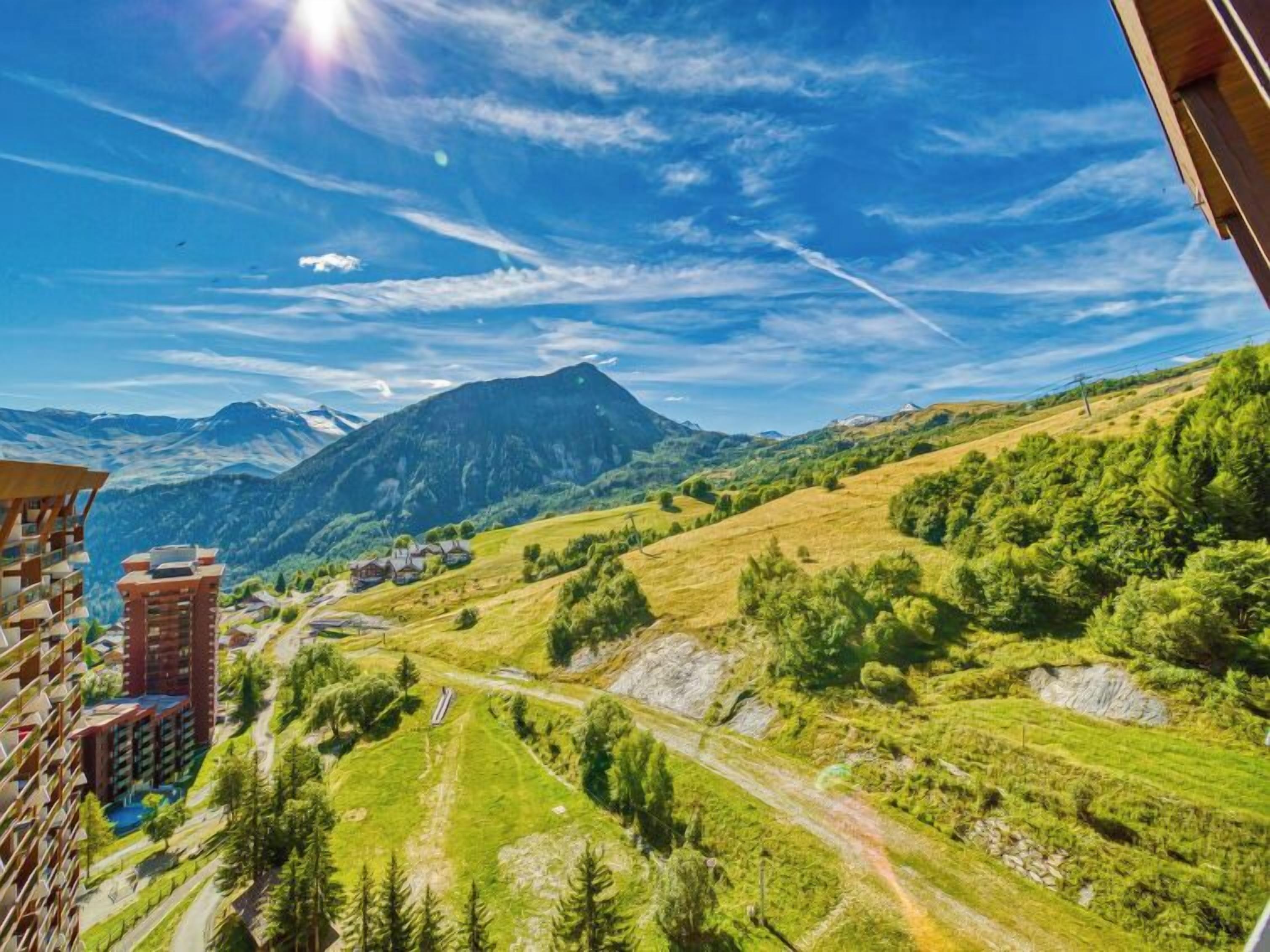 Un paisaje montañoso con cielo despejado, una carretera y un edificio de varios pisos.