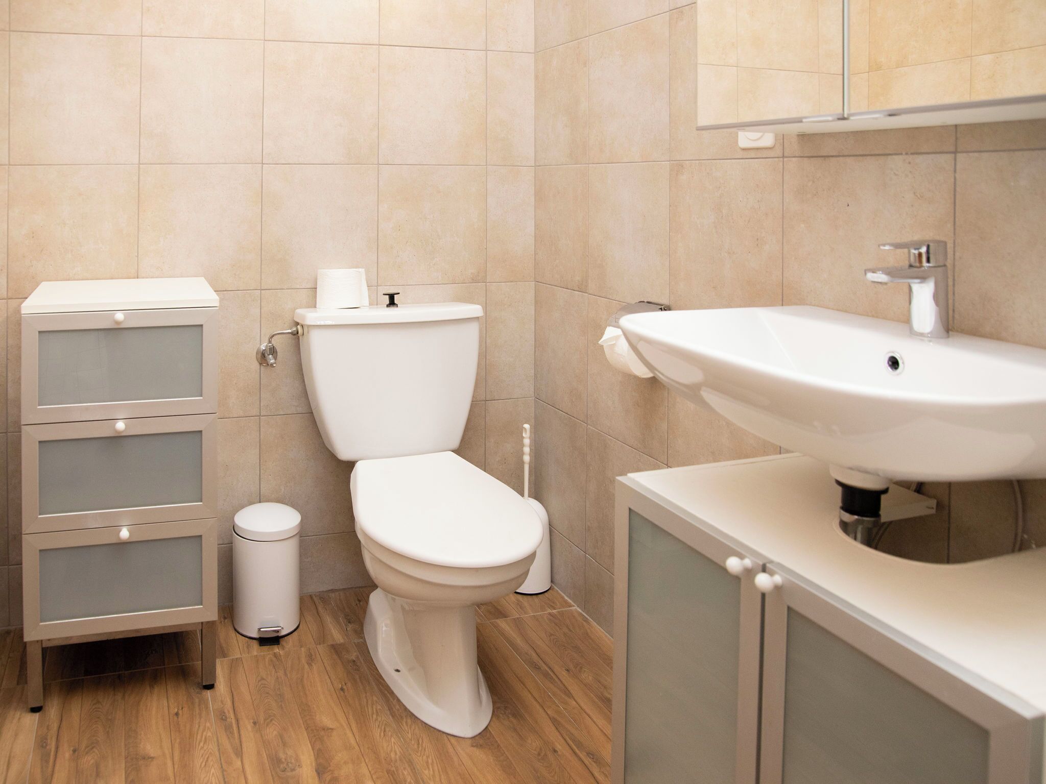 Een badkamer met toilet, wastafel en kast.