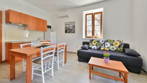 Un ambiente compatto con angolo cottura, zona pranzo e area salotto.