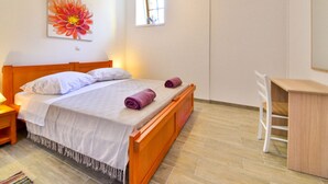 Una camera da letto con un letto in legno, biancheria da letto bianca, una scrivania e una sedia.