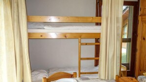 Een slaapkamer met stapelbedden en een eettafel voor twee personen.