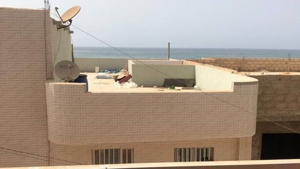 Un bâtiment doté d’un toit plat, d’antennes paraboliques et offrant une vue sur la mer.