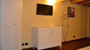 A room with a white cabinet, a mounted TV, and a wall art piece. - Dimora 4 Spade (Verona)