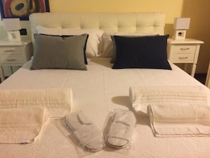 A neatly made bed with pillows, a white headboard, and a bedside table with a lamp. - Dimora 4 Spade (Verona)