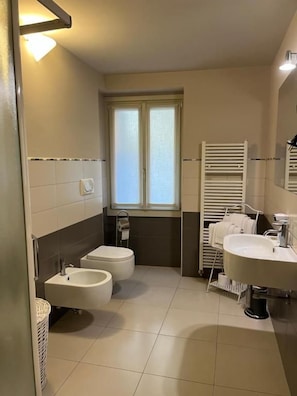 A bathroom with two sinks, a bidet, a window, and a towel rack. - Dimora 4 Spade (Verona)