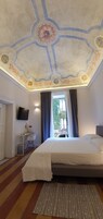 A hotel room with a large bed, a desk, a TV, and a view of the outside.