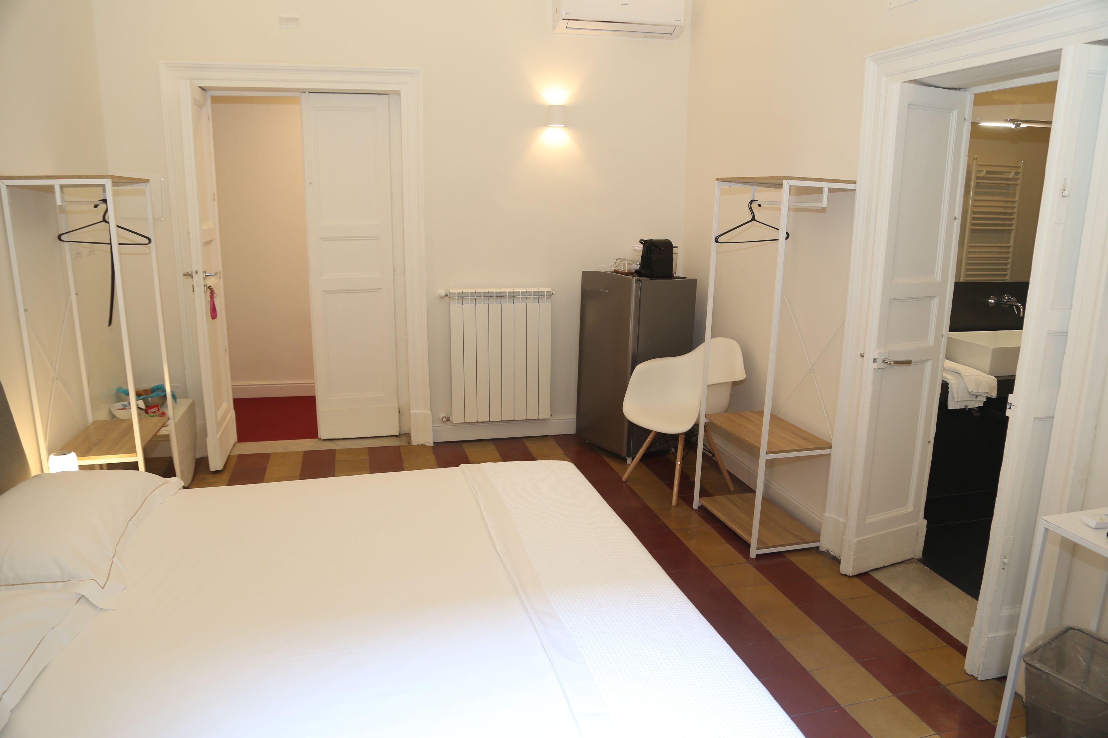 A bedroom with a bed, a wardrobe, a radiator, and a chair.