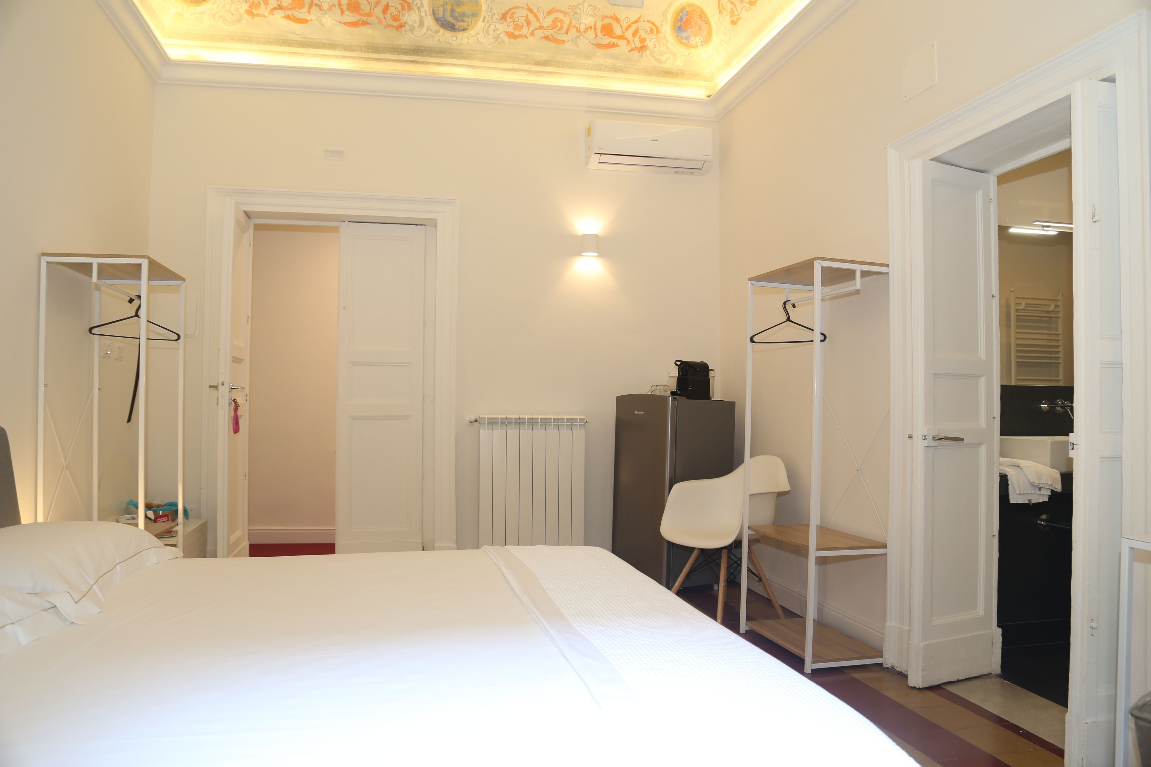 Una habitación de hotel con una cama, un armario, una silla y un radiador.