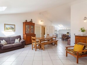A spacious living area with a wooden dining table, a sofa, and a cabinet.