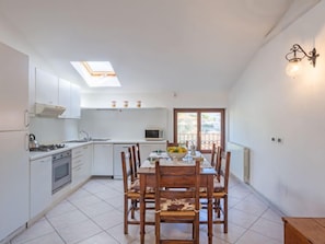 A compact kitchen with white cabinets, a gas stove, and a skylight.