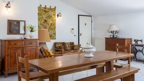 A dining area with a wooden table, benches, and a floral tapestry on the wall.