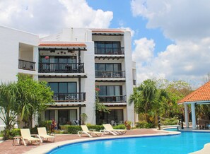 Un hotel con piscina, varios balcones y sillones de descanso.