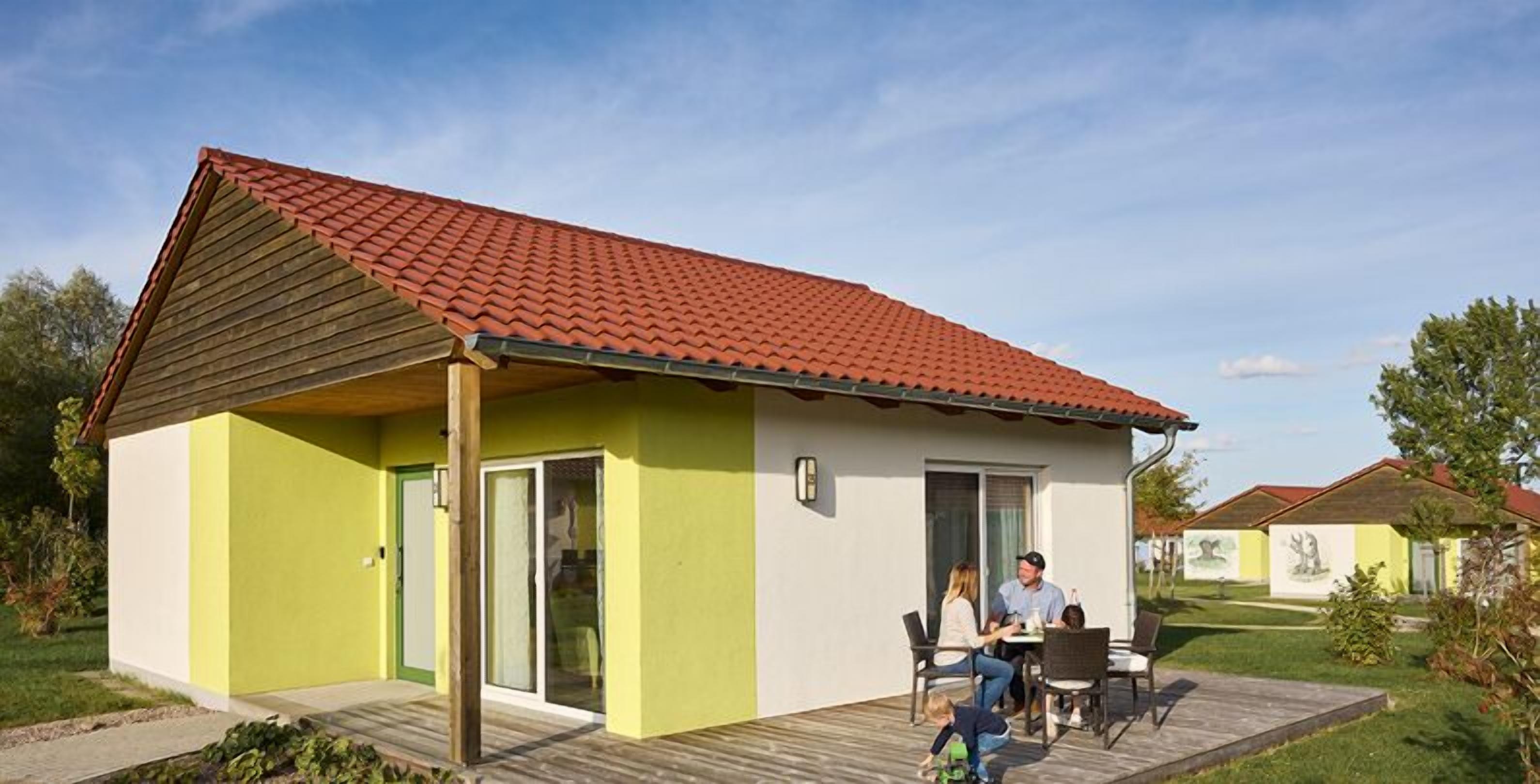 Ein kleines, eingeschossiges Haus mit rotem Ziegeldach und einer Fassade in Grün-Weiß.