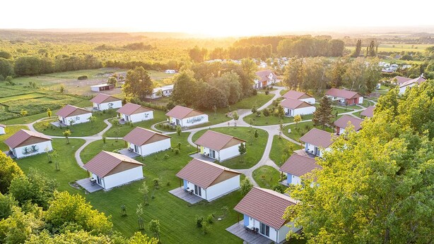Zona residencial con varias casas blancas de tejados rojos, dispuestas en forma de semicírculo alrededor de un espacio verde central.