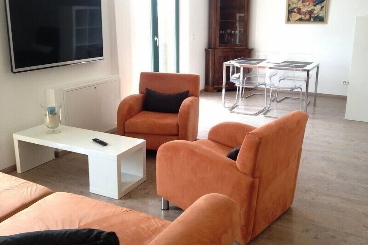 Ein Wohnzimmer mit einer Couch, einem Couchtisch, einem Fernseher, einem Schrank und einem Bild an der Wand.