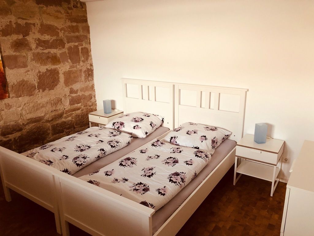 A double bed with floral bedding, a white headboard, and two bedside tables with lamps.