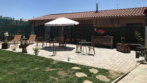 Une terrasse avec des meubles d’extérieur, un parasol blanc et des plantes en pot.