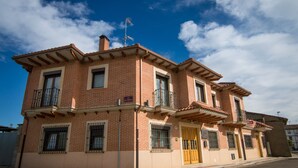 Un immeuble de deux étages avec une façade en briques, de nombreux balcons et une porte jaune.