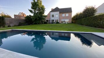 En säsongsöppen utomhuspool, parasoller och solstolar