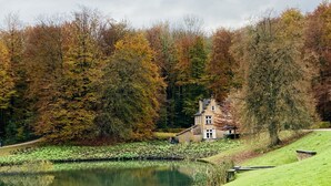 A house by a lake with a pond in the foreground and trees in autumn colors in the background. - B&B Aline Florentine (Kortenberg)