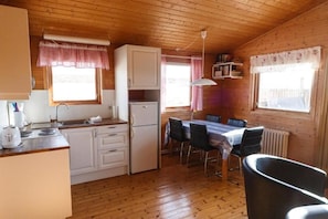 Eine Holzhütte mit Küchenzeile, Esstisch und Stühlen.