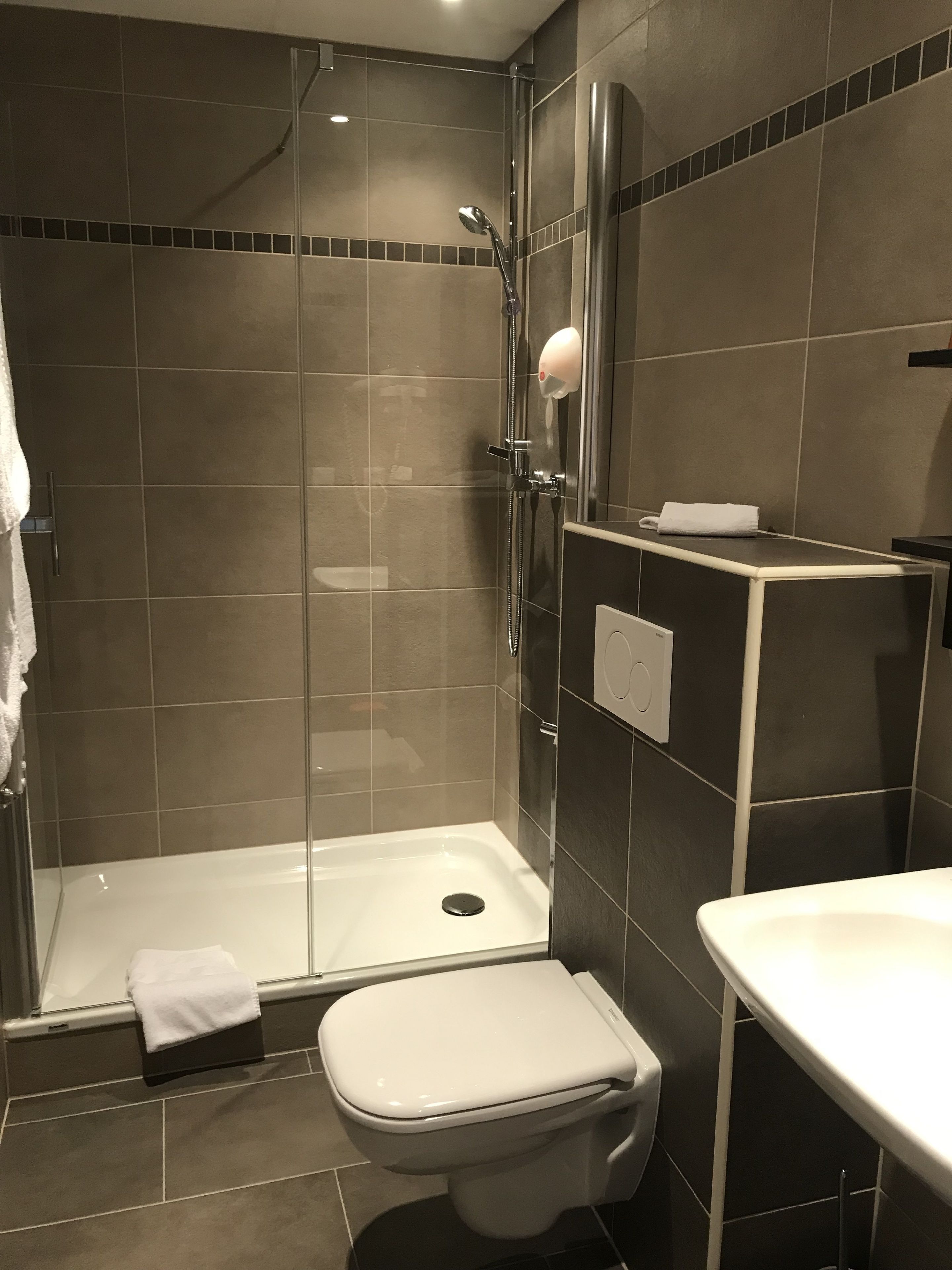 Une salle de bain moderne avec une douche à parois de verre, des toilettes et un lavabo.