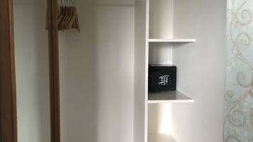 A bedroom with a bed, a wardrobe, and a shelf unit.