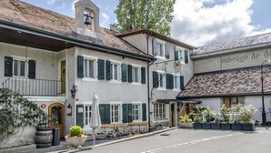 Un edificio europeo tradicional con letrero de restaurante, mesas al aire libre y una torre de campanas.