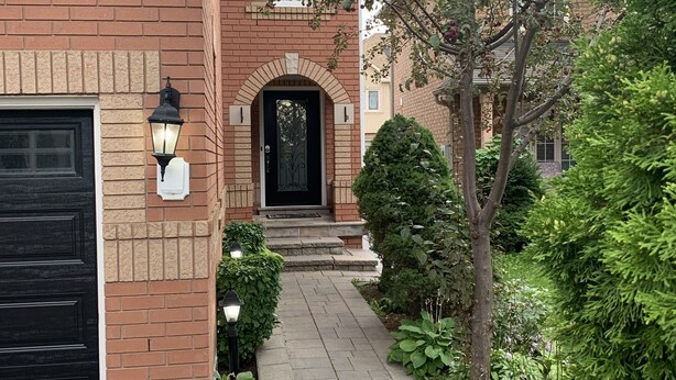 Un edificio de ladrillo con una puerta de garaje negra, una puerta principal negra y un sendero que lleva a la entrada.