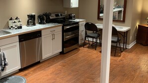 Una cocina moderna con armarios blancos, electrodomésticos de acero inoxidable y suelo de madera.