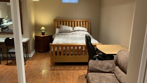 Una habitación compacta con cama, escritorio, silla y sofá.