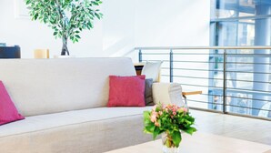 Una sala de estar moderna con un sofá, cojines, una mesita y una planta en maceta.