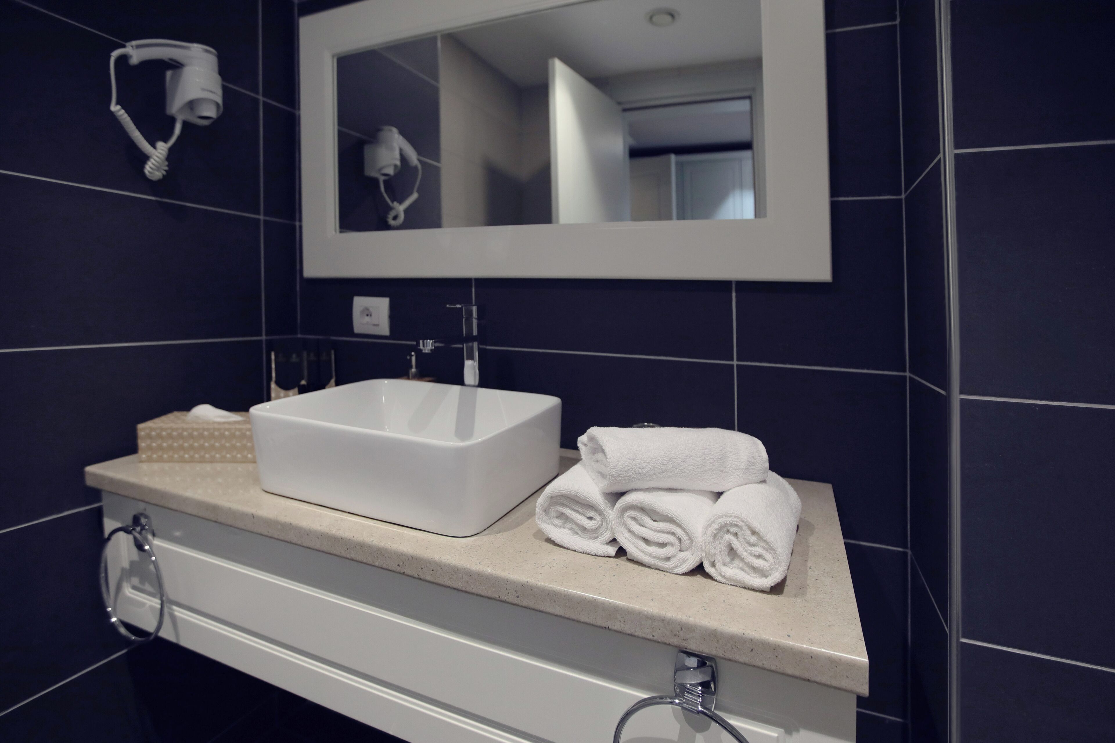 A bathroom with a white sink, a mirror, and a towel rack.