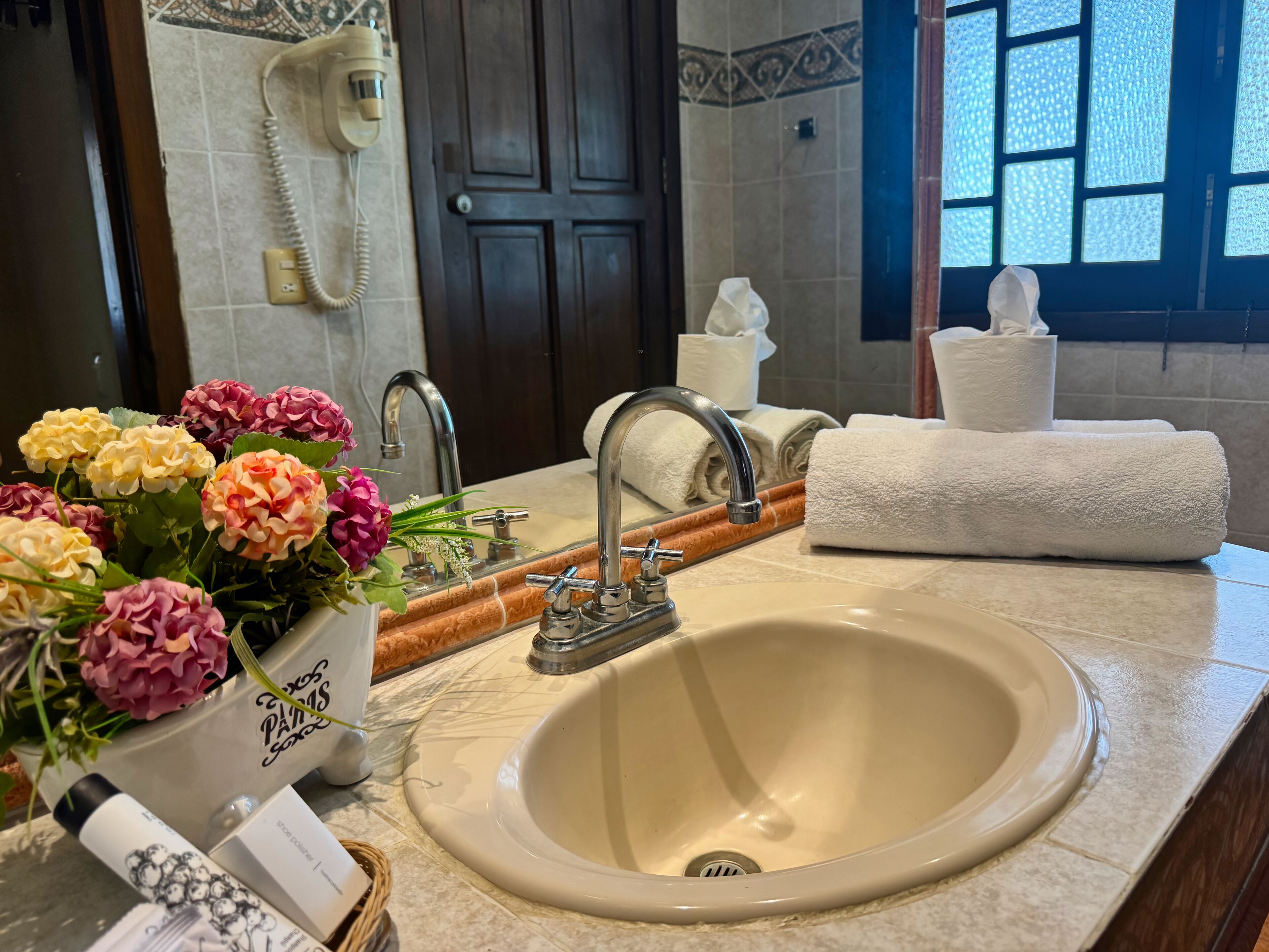 A bathroom with a sink, mirror, and a telephone.
