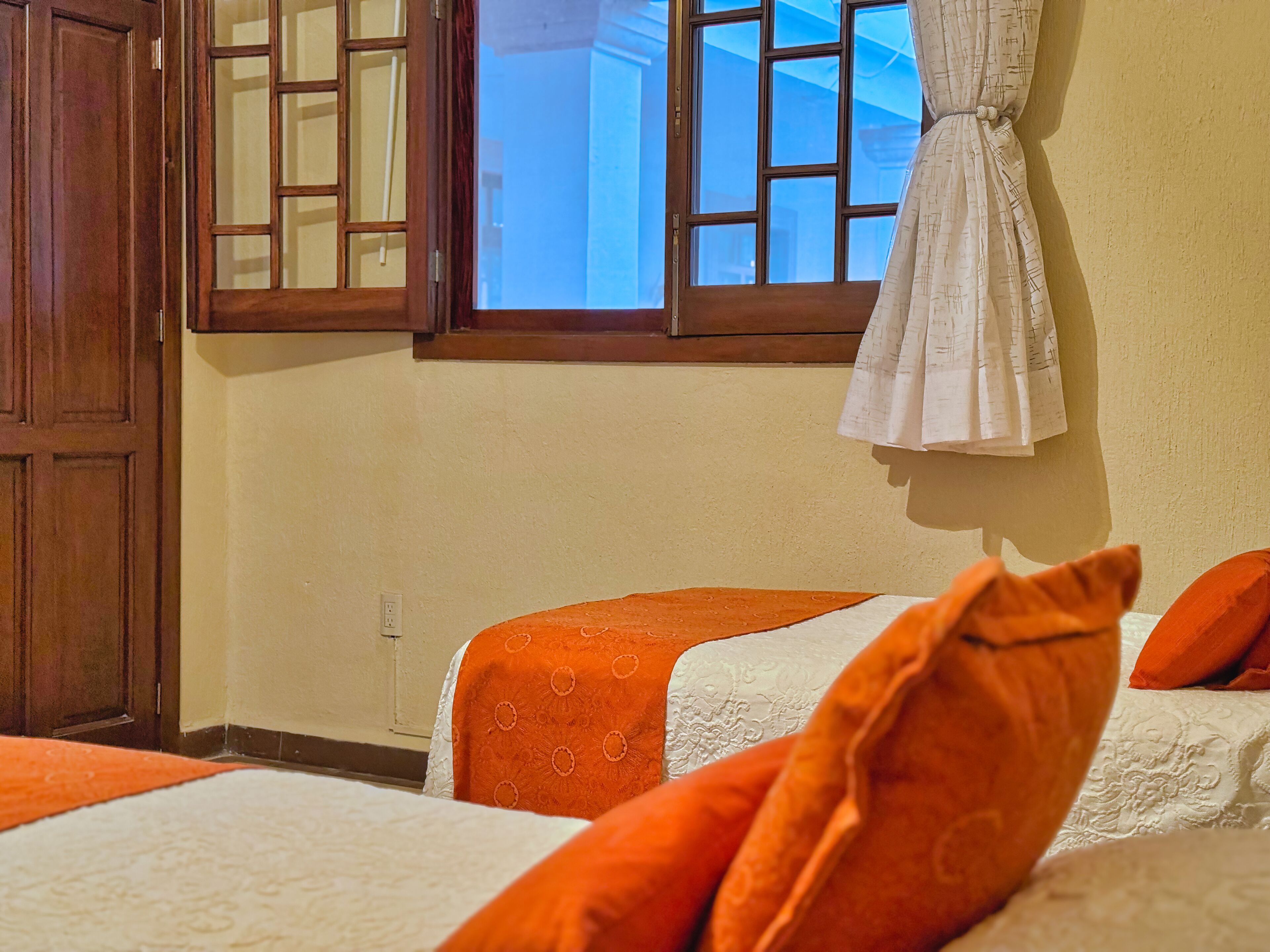 Una habitación de hotel con dos camas, un ventanal con vistas y una cortina.