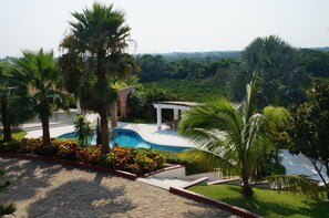 A pool area with palm trees, a gazebo, and a stone pathway.