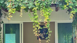 Un espacio exterior techado con asientos, una decoración colgante y vistas al jardín.